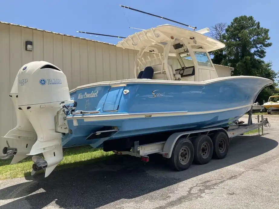 A pale-blue twin-outboard center console on a triple-axle trailer
