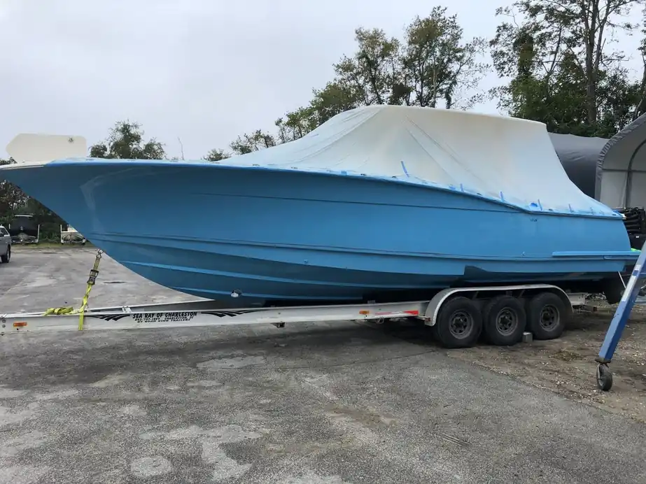 Freshly painted blue hull on a triple-axle trailer with the deck still wrapped