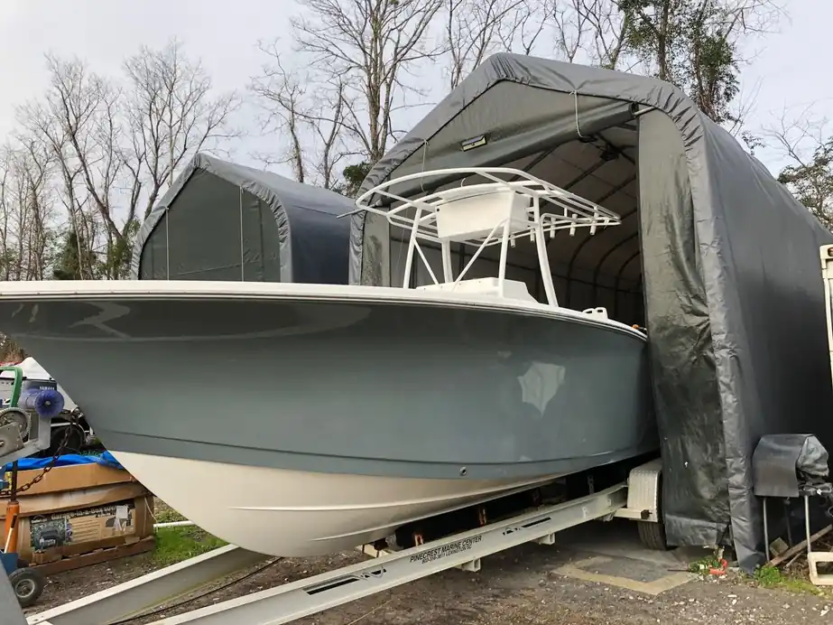 A grey-green refinished hull with its T-top backing out of a covered paint bay
