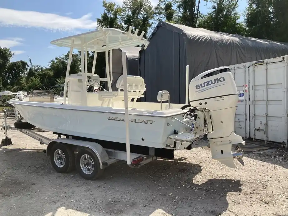 A white center console with T-top on its trailer beside the covered bays after detailing