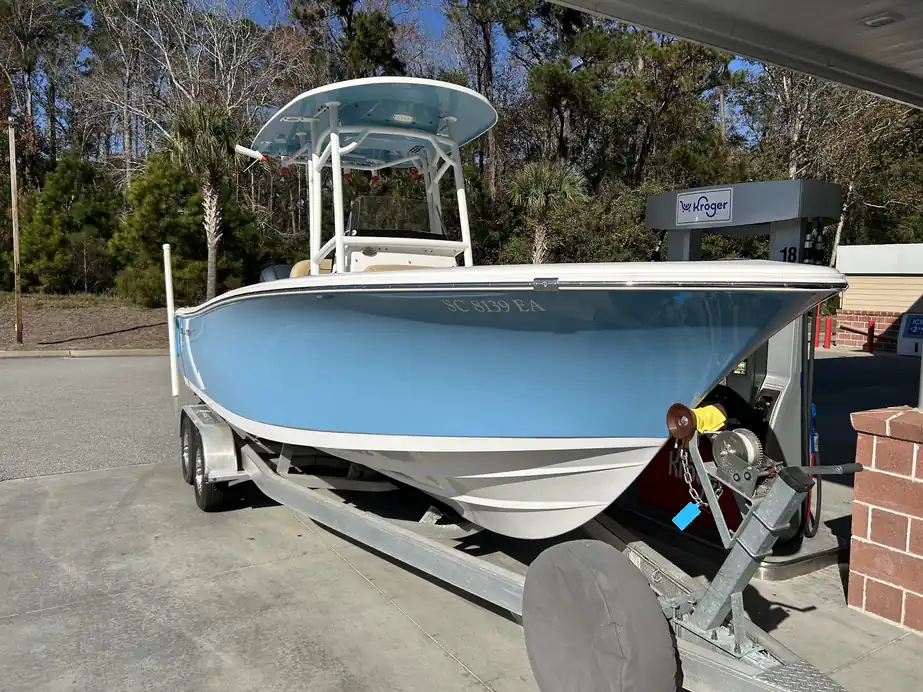 Pale-blue center console with a hard top on a trailer in the yard