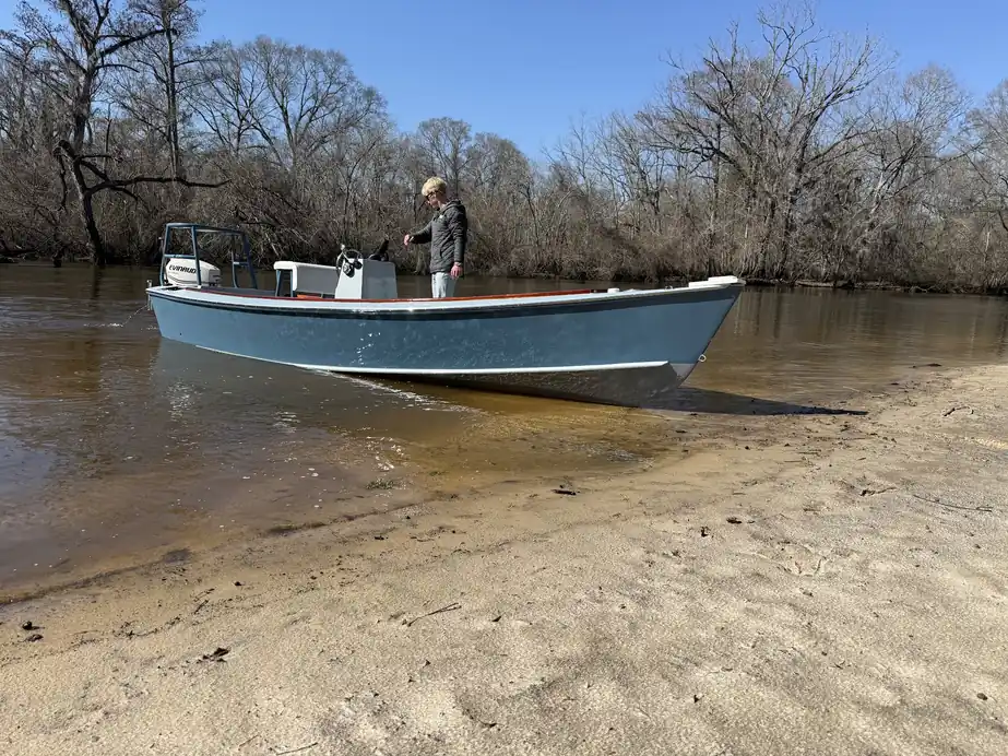 Pale-blue skiff on a sandy creek bank