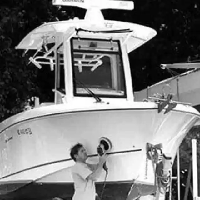 A black and white photo of a worker polishing a white hull by hand